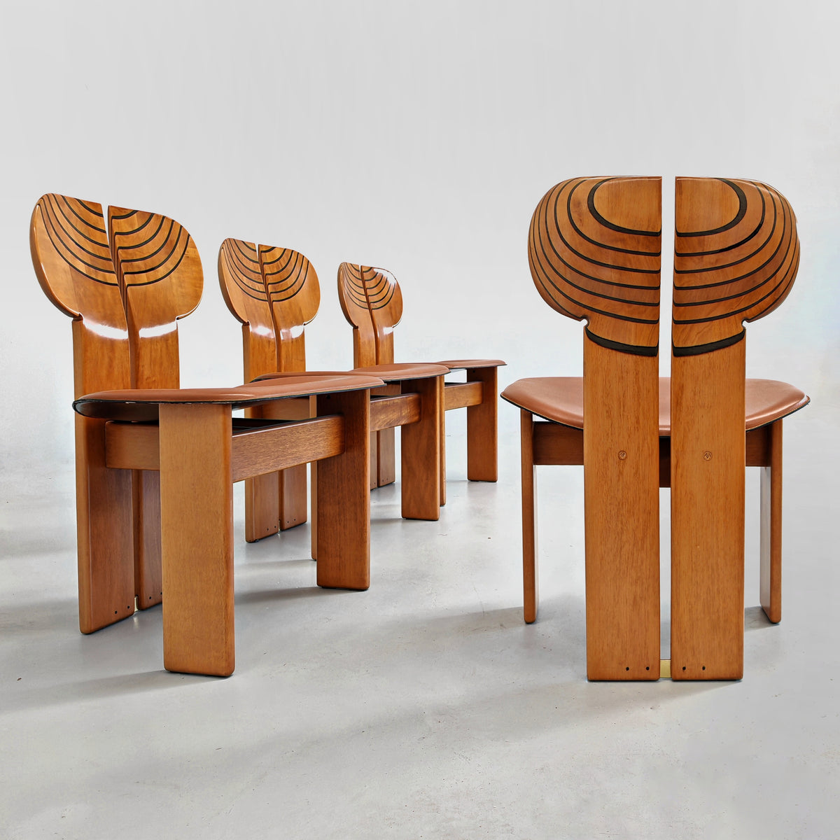 Set di quattro sedie Africa in legno chiaro con sedute color cuoio viste di tre quarti